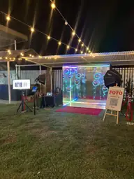 Cabina espejada bajo guirnaldas de luz en un jardín
