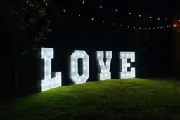 Letras LOVE Vintage iluminadas en un jardín de noche